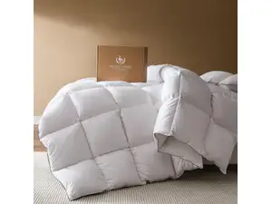 White Pacific Coast Feather & Down Comforter on a bed next to a sliding glass door with two brown pillows at the head of the bed.