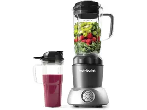 A Nutribullet personal blender filled with a berry smoothie sits on a counter next to its ingredients.