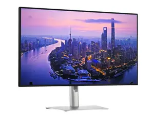 A widescreen monitor displays a high-resolution image of red rock formations in a desert landscape, framed by black studio speakers on a sleek desk setup.