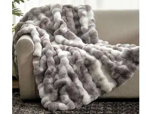 A cat lays on a faux fur blanket