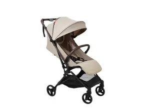 Black Mamazing stroller outside on a patio, set in front of a wooden fence and rock garden, with palm trees beside it.
