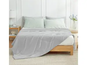 Gray Cozy Bliss comforter on a full-sized bed in a bedroom with beige walls and a brown headboard.