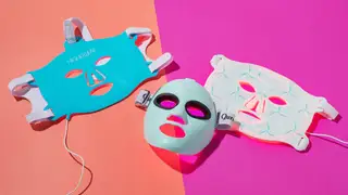 Three red light LED therapy masks on a pink background