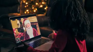 A young child looking at a laptop showing an image of Santa Claus.