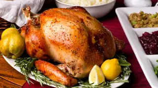 Cooked turkey on a plate with fruit and herbs.