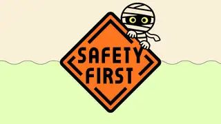 A mummy peeks over an orange sign that says Safety Firts