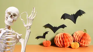 A skeleton gives the A-OK sign to some Halloween decor