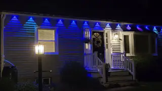 Govee Permanent Outdoor Lights 2 Pro illuminated in blue hung horizontally on a white house.