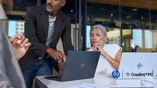 Man leaning over an HP in an office next to a woman who also has an HP EliteBook X