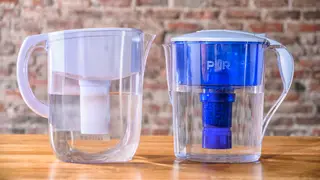 Two water pitchers against a brick wall