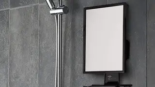 A fogless shower mirror being used for music and for a man to shave.
