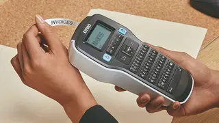 A woman using a label maker to organize her work files.