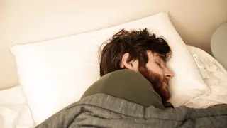 Our photographer's model sleeps soundly (or pretends to) on a large, soft white pillow.