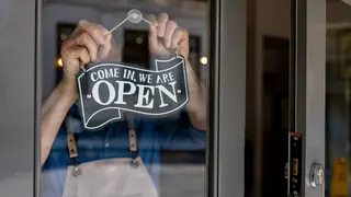 Close-up on a business owner hanging an open sign on the door of their restaurant