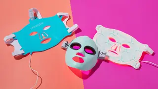 Three red light LED therapy masks on a pink background