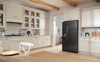 A black stainless steel refrigerator is a focal point in this white kitchen