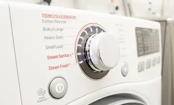 A control panel shows cycle options on the front control panel of a white dryer