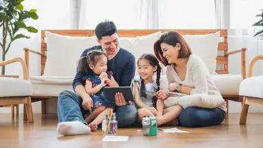 Family huddled around a tablet in the living room