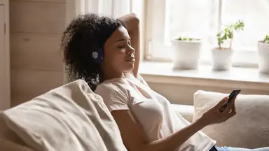 Woman sits on her couch meditating
