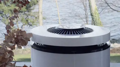 CleanAirZone bio-based air purifier in front of an outdoor landscape of trees and water