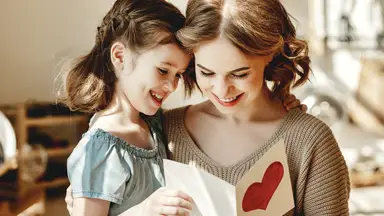 A mother and daughter read a card together