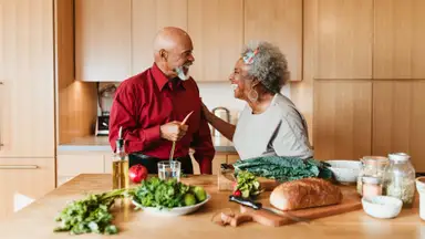 A couple laughs in their wood-paneled kitchen.