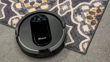 A Shark IQ AV1010AE Robot Vacuum cleaning a carpet.