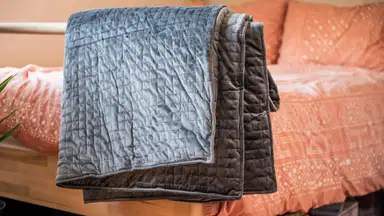 the gravity blanket hangs on the end of a bed