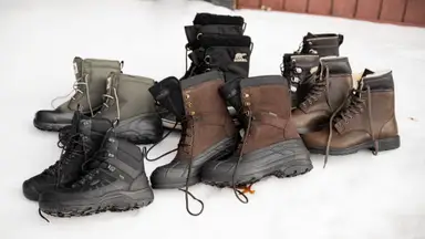 A wide selection of men's winter boots, sitting on a bank of snow.