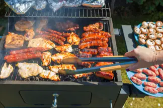 A person flipping meat on a barbecue