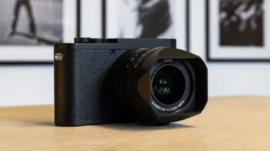 A Leica Q2 Monochrom camera sits on a wooden table in an art gallery.