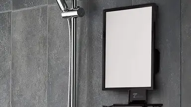 A fogless shower mirror being used for music and for a man to shave.