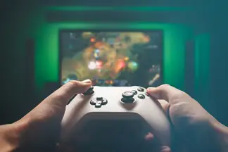 A man's hands hold a gaming controller while playing a RPG on a TV.