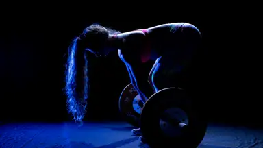 A barbell being used by a bodybuilder in his garage gym.