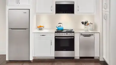 A small kitchen with a refrigerator, an oven range, utensils on the countertop, and so on.