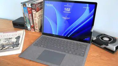 Microsoft Surface 5 Laptop on top of wooden desk surrounded by books.