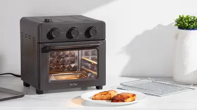 Our Place Wonder Oven on countertop behind small dish with salmon on top, next to potted plant and wire rack.