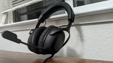 The HyperX Cloud III headphones leaning against a white window.