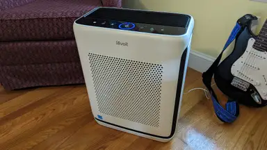 The Levoit Vital 200S air purifier is installed in a home for testing, next to a guitar and chair.