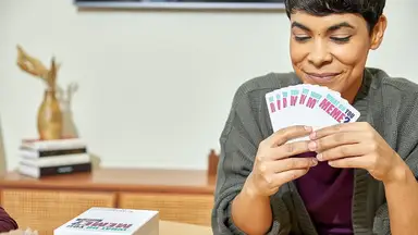 A woman playing 'What Do You Meme?' with her friends.