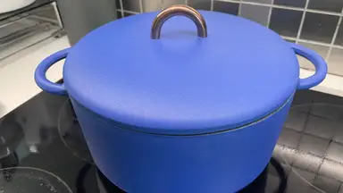 Great Jones 3.5-quart Dutch Baby in Blueberry color with lid attached on top of electric eye on stove.