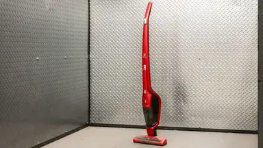 A red Electrolux Ergorapido standing upright in front of  a metallic background.