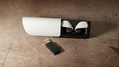 The Sony Pulse Explorer earbuds inside of their case above a USB dongle.