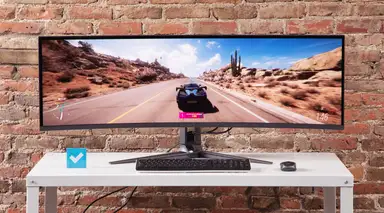 The Asus ROG Swift PG49WCD on a white table with a brick wall in the background.