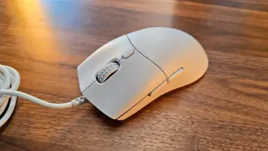 The NZXT Lift 2 Symm mouse on a wood table.