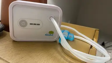 A white Nozebot nasal aspirator kit sits on a wooden tabletop.