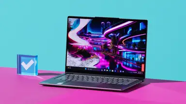 The Lenovo Slim 7 with a abstract wallpaper on screen on top of a purple desk next to a blue paper weight.