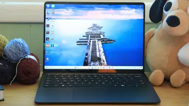 An opened Microsoft Surface Laptop 7th Edition on a desk next to a stuffed animal and balls of yarn.