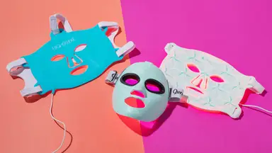 Three red light LED therapy masks on a pink background
