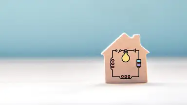 A small wooden toy house block with an electrical circuit graphic overlay